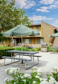a patio with two picnic tables and two umbrellas