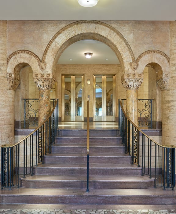 a long hallway with columns and stairs and doors