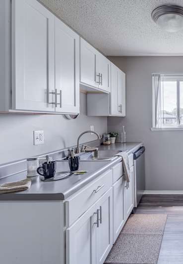 A kitchen with white cabinets and a black refrigerator.