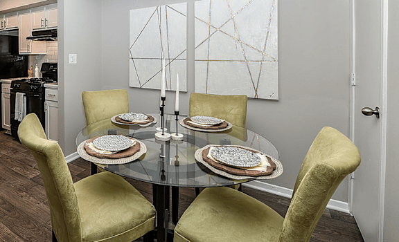A dining room with a glass table and yellow chairs.