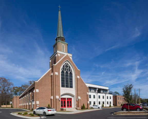 a church with a tall steeple and a building with a red door