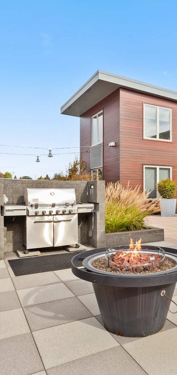 A patio with a fire pit and chairs.