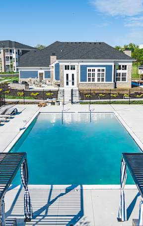 A pool with sun loungers and a building in the background.