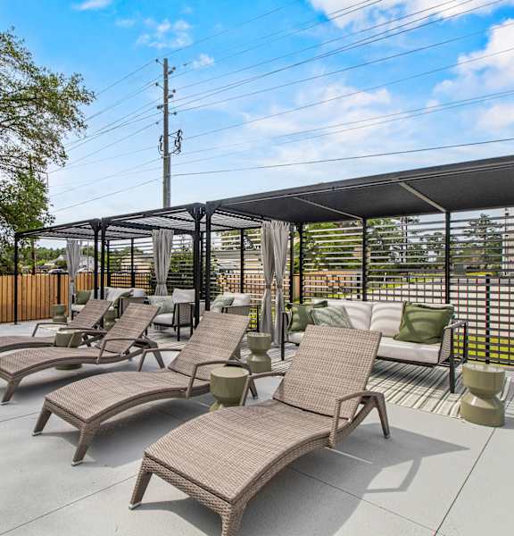 A patio with a black awning and brown chairs.