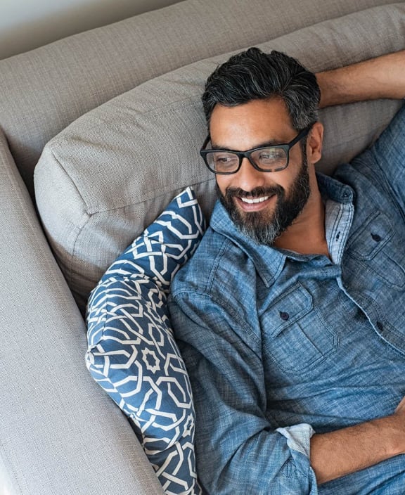 a man laying on a couch with his head on a pillow