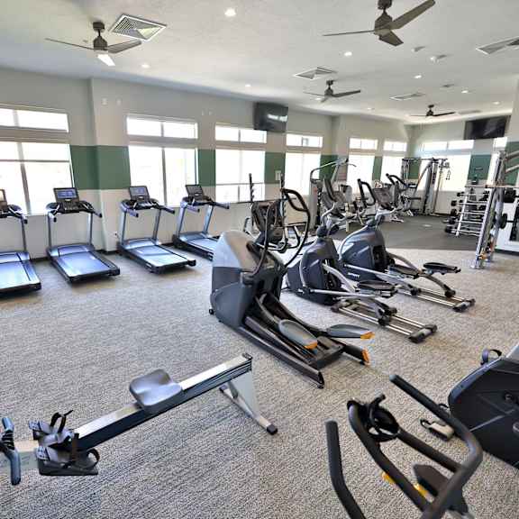 a gym with cardio equipment and windows in a building