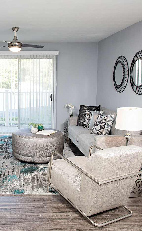 A living room with a grey couch, a rug, and a ceiling fan.