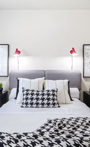 a bedroom with a large bed with black and white pillows and two night stands