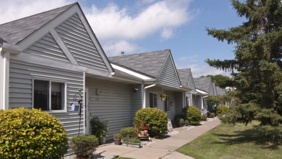 a row of gray houses with bushes in front of them
