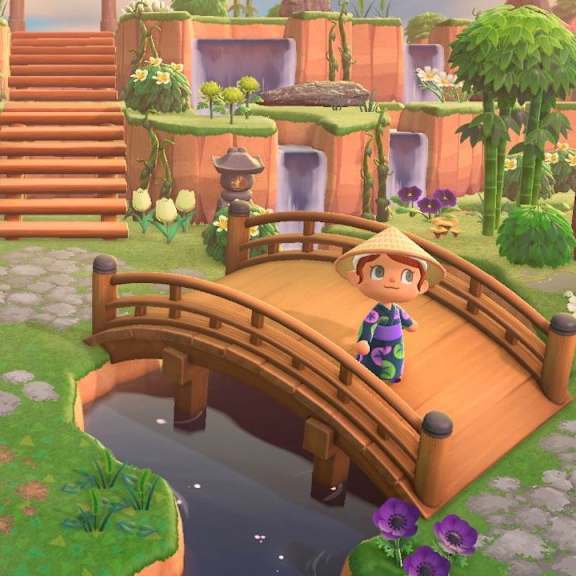 A character in a blue outfit stands on a bridge in a lush, green landscape.