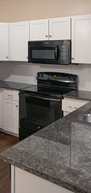 a kitchen with white cabinets and a black stove and refrigerator