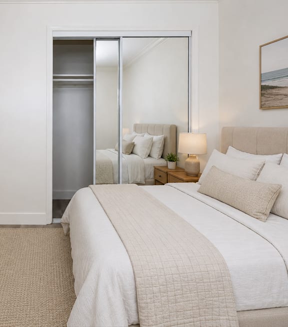 A bedroom with a bed, a plant, and a painting on the wall.