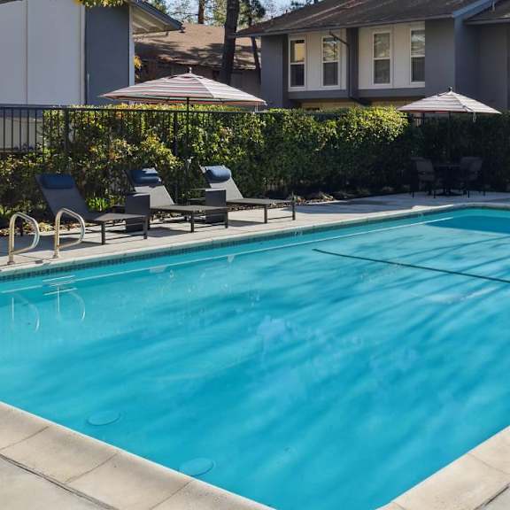 A swimming pool surrounded by a concrete patio and a row of houses.