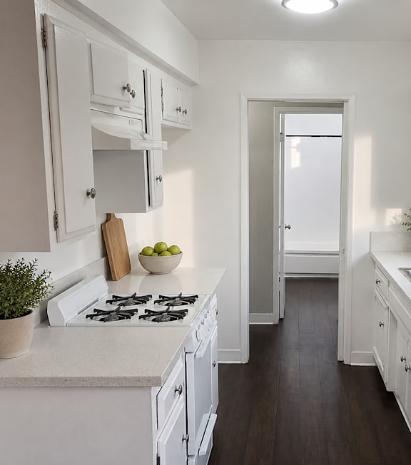 A white kitchen with a stove, sink, and cabinets.