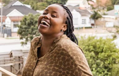 a woman laughing on a balcony with a city in the background