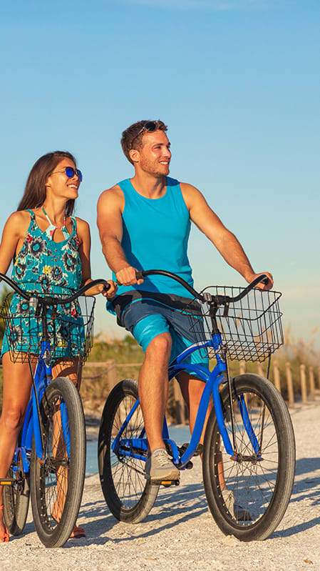 Lifestyle photo of couple on bikes at the beach at Tuscany Place Apartments, Florida