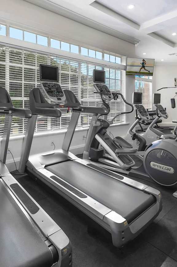 a workout room with treadmills and a tv