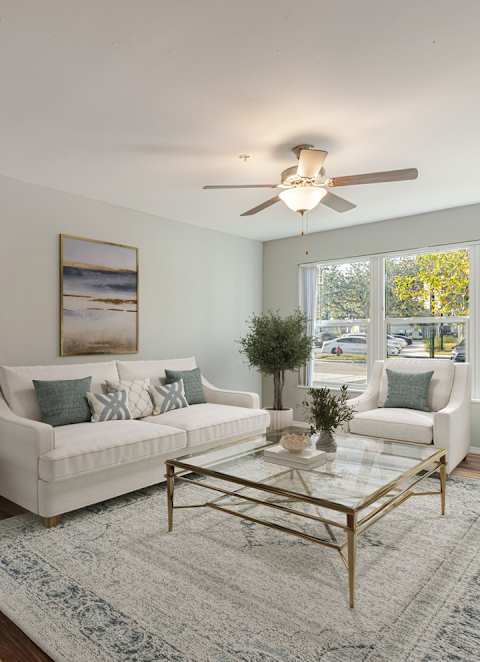 A living room with a white couch and a glass coffee table.