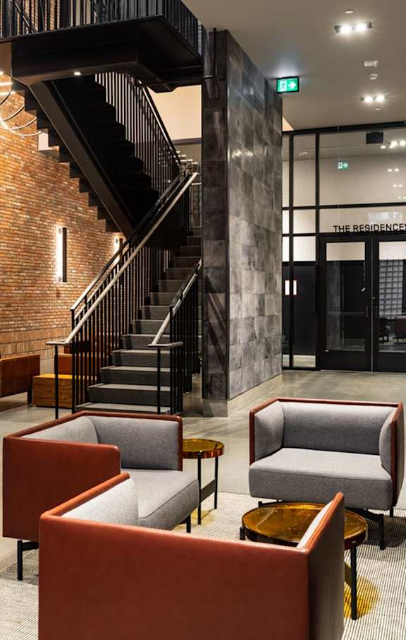 A modern interior with a staircase, chairs and a fireplace.at Raymond Block, Edmonton