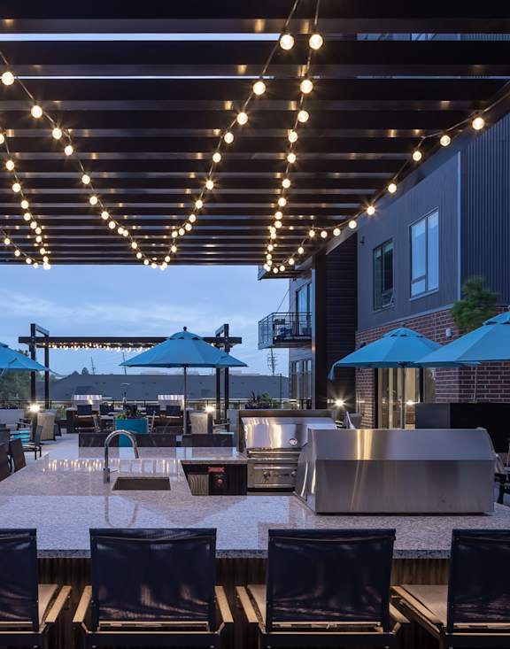 A patio with tables and chairs under a canopy with lights strung up.