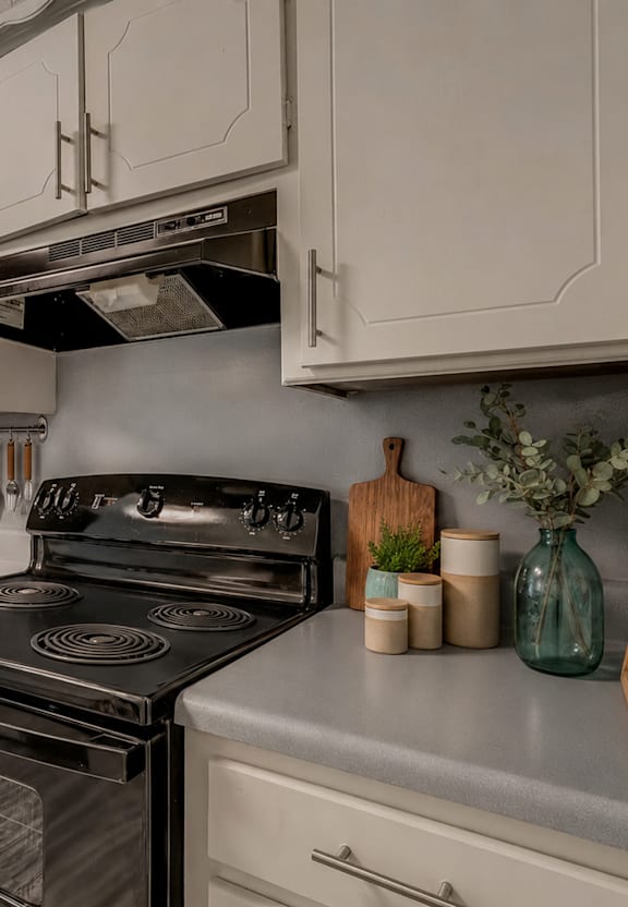 A black stove top oven sits in a kitchen with white cabinets.