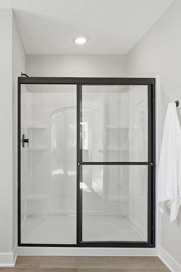 A white bathroom with a black framed shower door.