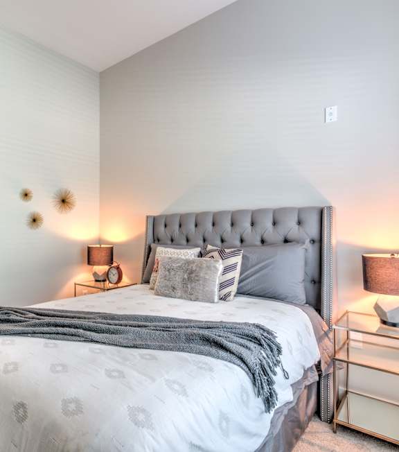 A bedroom with a large bed and a nightstand with a lamp A bedroom with a large bed and a nightstand with a lamp at Highland Row Apartments, Memphis, TN, 38111