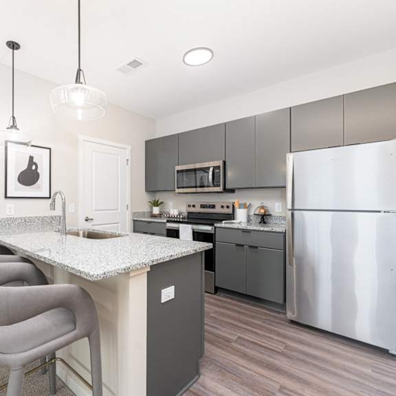 A kitchen with a white counter top and grey chairs.