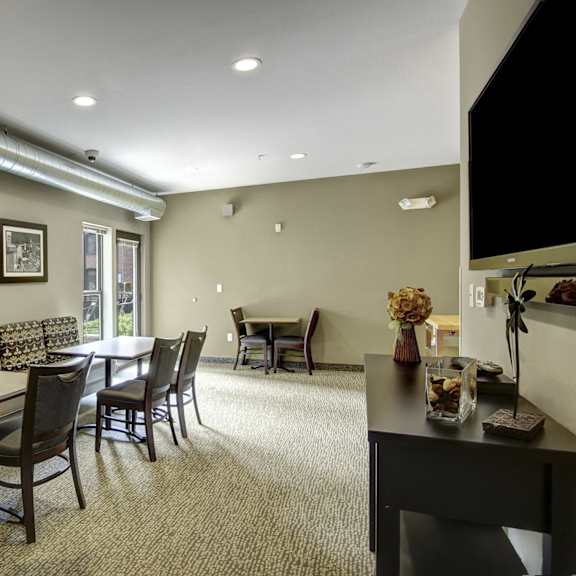 A room with a variety of tables and chairs with booth-style chairs and a TV at Loft at Farmers Market. 