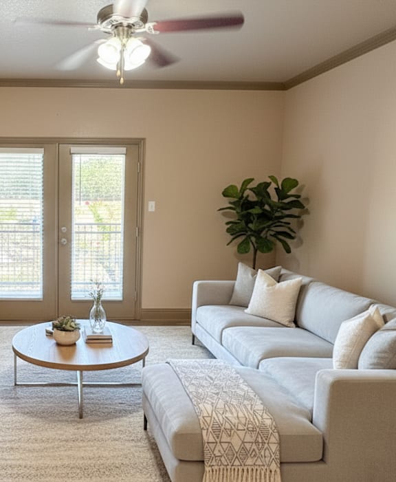A living room with a sofa, a coffee table, and a ceiling fan.