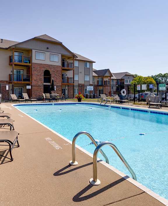 Outdoor pool at Regency Woods Apartments surrounded by lounge chairs.