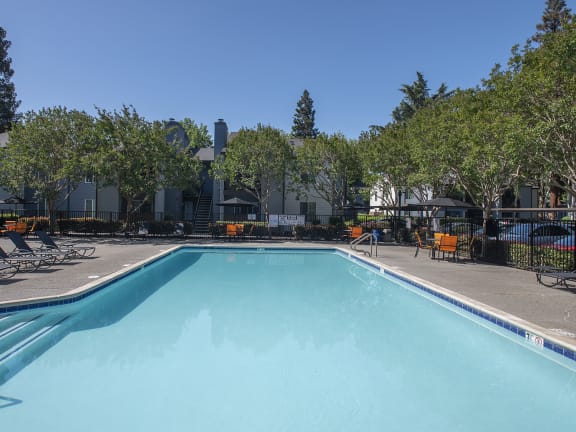 Pheasant Pointe apartments swimming pool, spa, and pool deck with lounge chairs, tables and umbrellas 