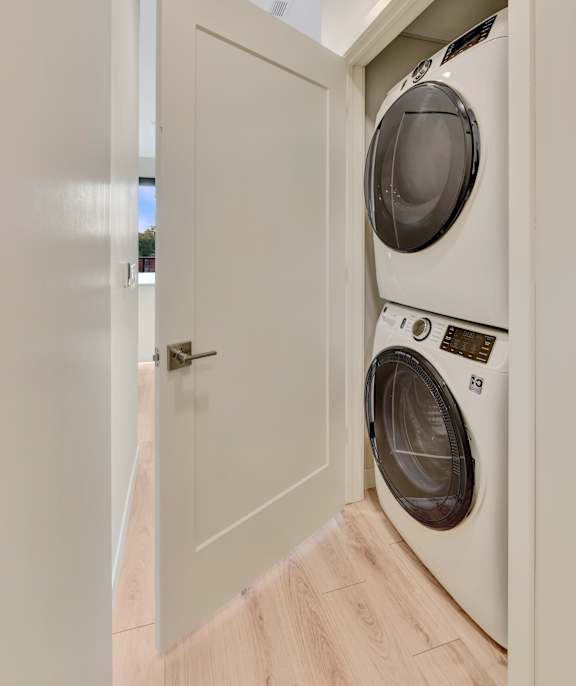A white door opens to a laundry room with a washer and dryer.
