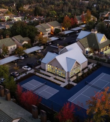 Drone Shot at Dusk showing the entire community from above. Leasing office, tennis courts and swimming pool are visible. 