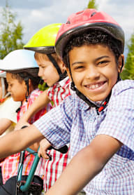 A group of children wearing helmets and riding bikes.
