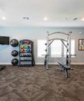 fitness center with a bench, squat rack, and dumbells