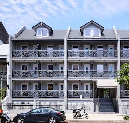 A grey building with a car and motorcycle parked in front.
