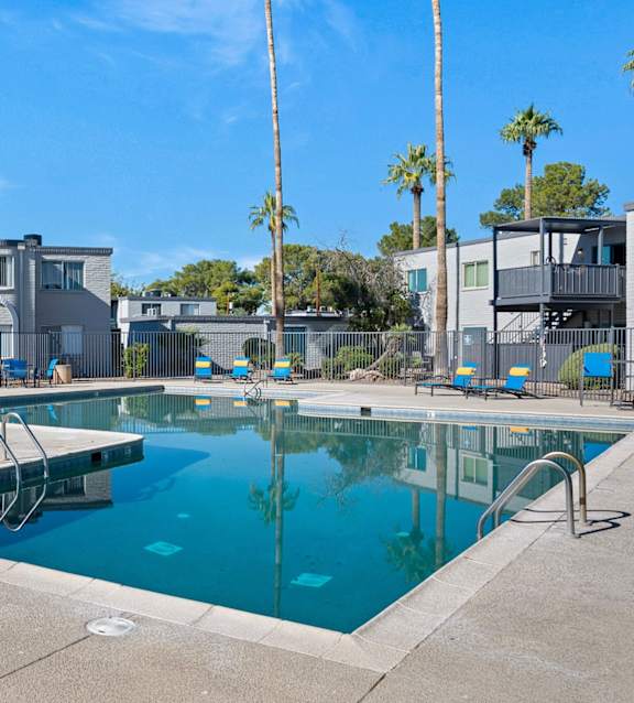 A large swimming pool with blue water and sun loungers.