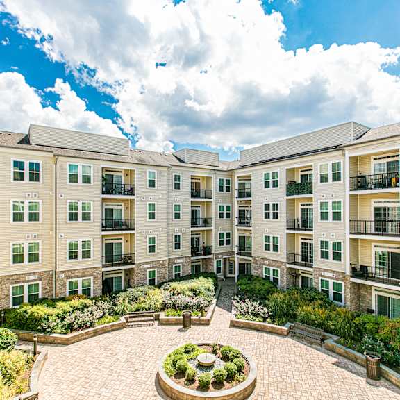 A brick building with a white porch and a black gate. at Kensington Place Apartments, Woodbridge