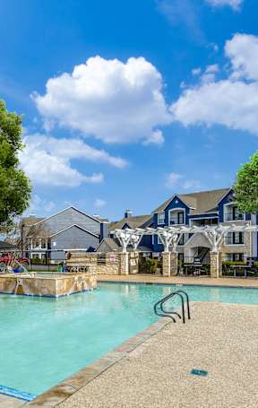 A pool surrounded by trees and a building in the background.
