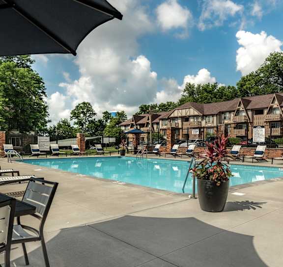 A large swimming pool in front of a house with lounge chairs around it in Dayton, Ohio at Autumn Woods Apartments, Miamisburg, OH, 45342