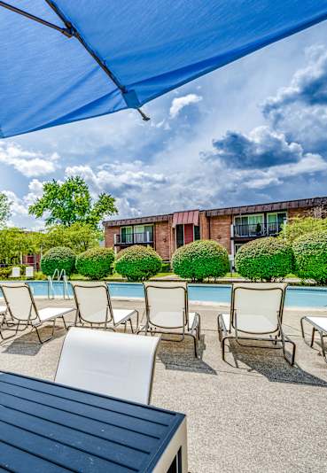 A blue umbrella is in the foreground of a poolside area.