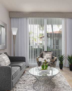 A living room with a grey couch, a glass coffee table, and a flat screen TV.