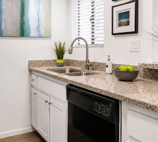 A kitchen with a black fridge and white cabinets.