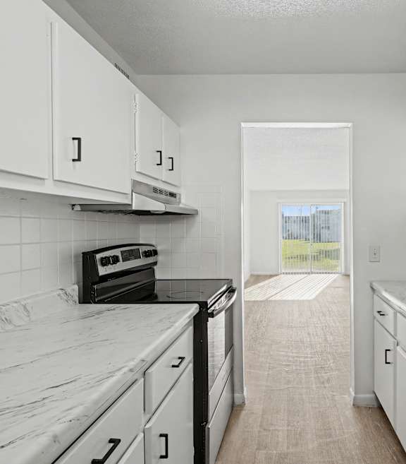 A kitchen with white cabinets and marble countertops.