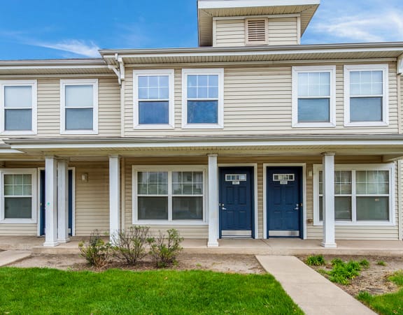 Exteriors of townhomes at Horace Mann in Gary, IN with white trim and blue doors and small grassy front yards