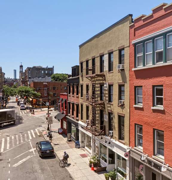 A street view of a city with buildings on either side and a car driving down the road.