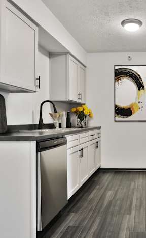 A modern kitchen with white cabinets and black appliances.