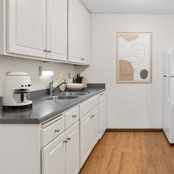 A kitchen with white cabinets and a wooden floor.