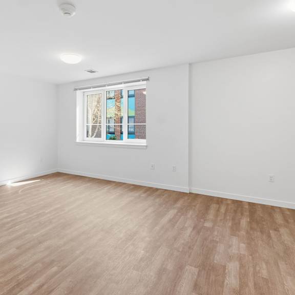 A room with wooden flooring and a window with a stained glass design.